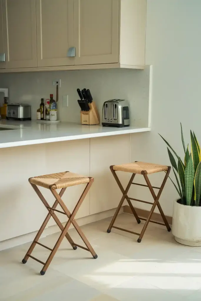 A kitchen setup with Lavish Home folding stools, showing them both unfolded in use and folded, illustrating their compact and versatile nature.