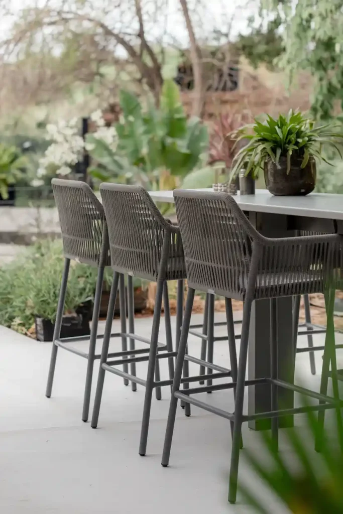 Outdoor Patio Bar Stools: Stylish outdoor bar stools made of weather-resistant materials, arranged around a patio table with greenery in the background.