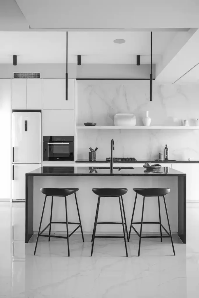 a minimalist Scandinavian-style kitchen island featuring light wood accents and a set of sleek, white bar stools with natural wood legs.