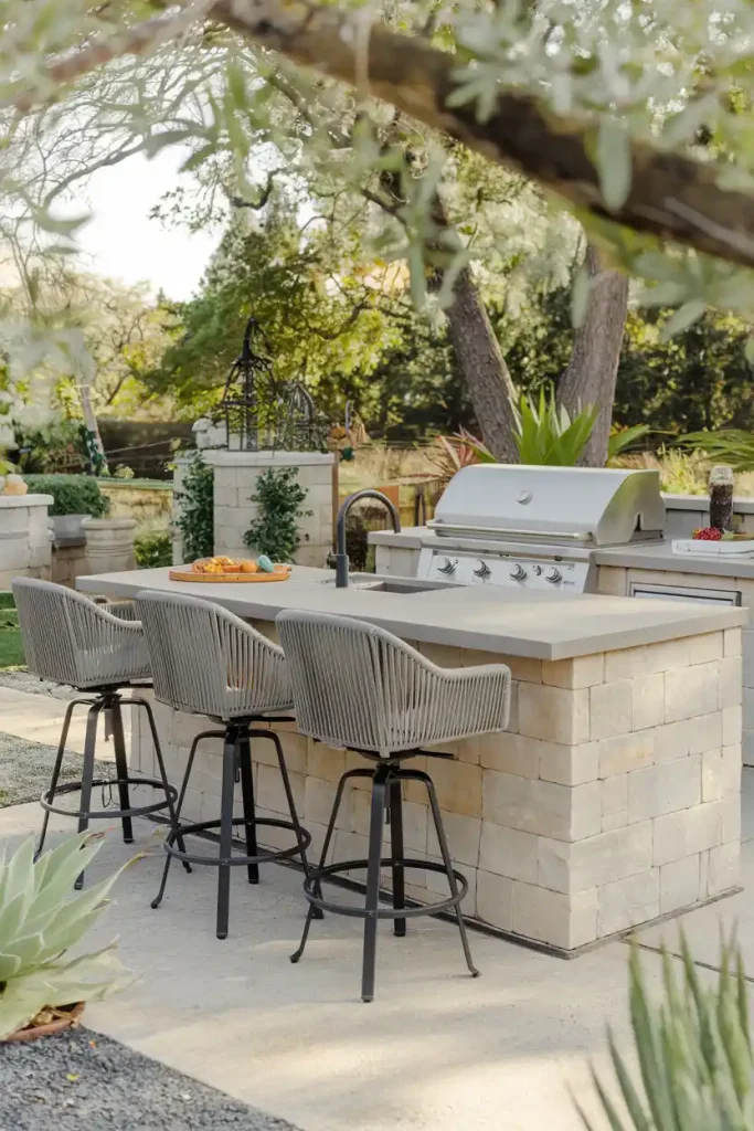 Outdoor Kitchen with Swivel Stools: An outdoor kitchen setup featuring weather-resistant swivel back stools around a stylish island, surrounded by greenery and outdoor decor.