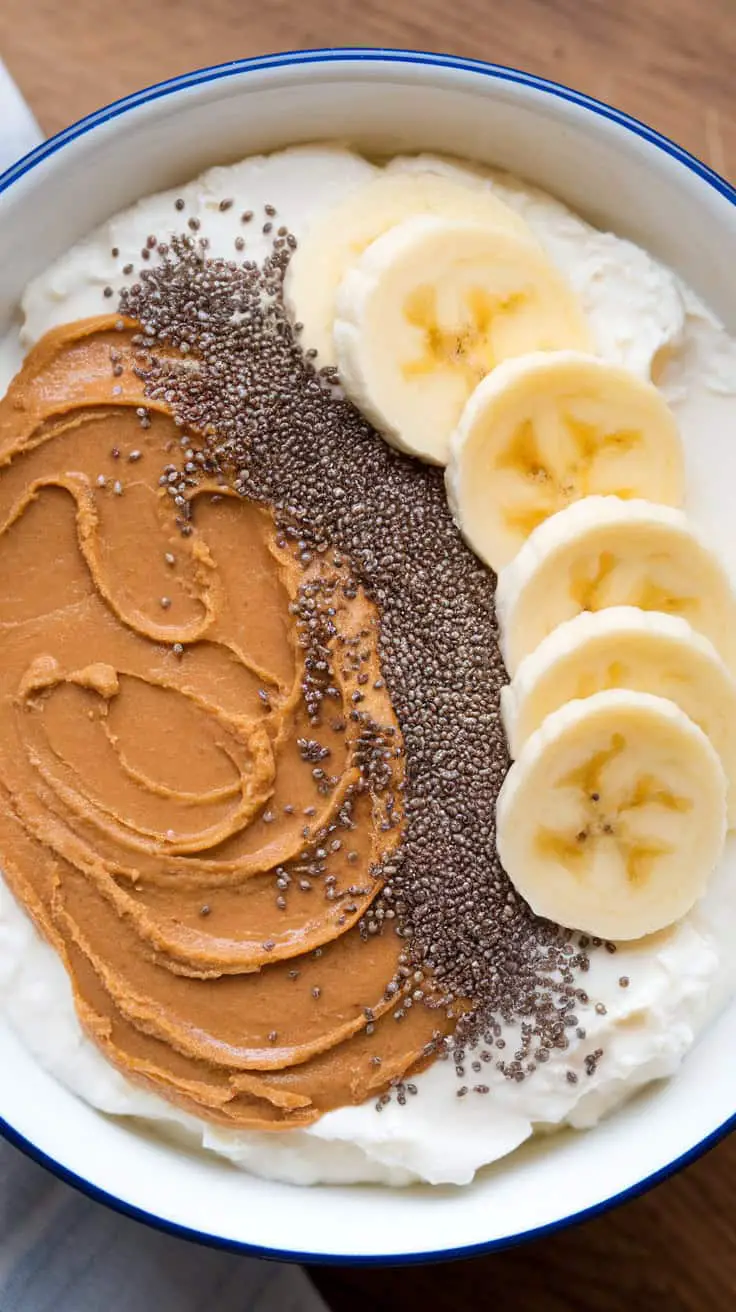 A bowl of peanut butter cottage cheese topped with banana slices and chia seeds.